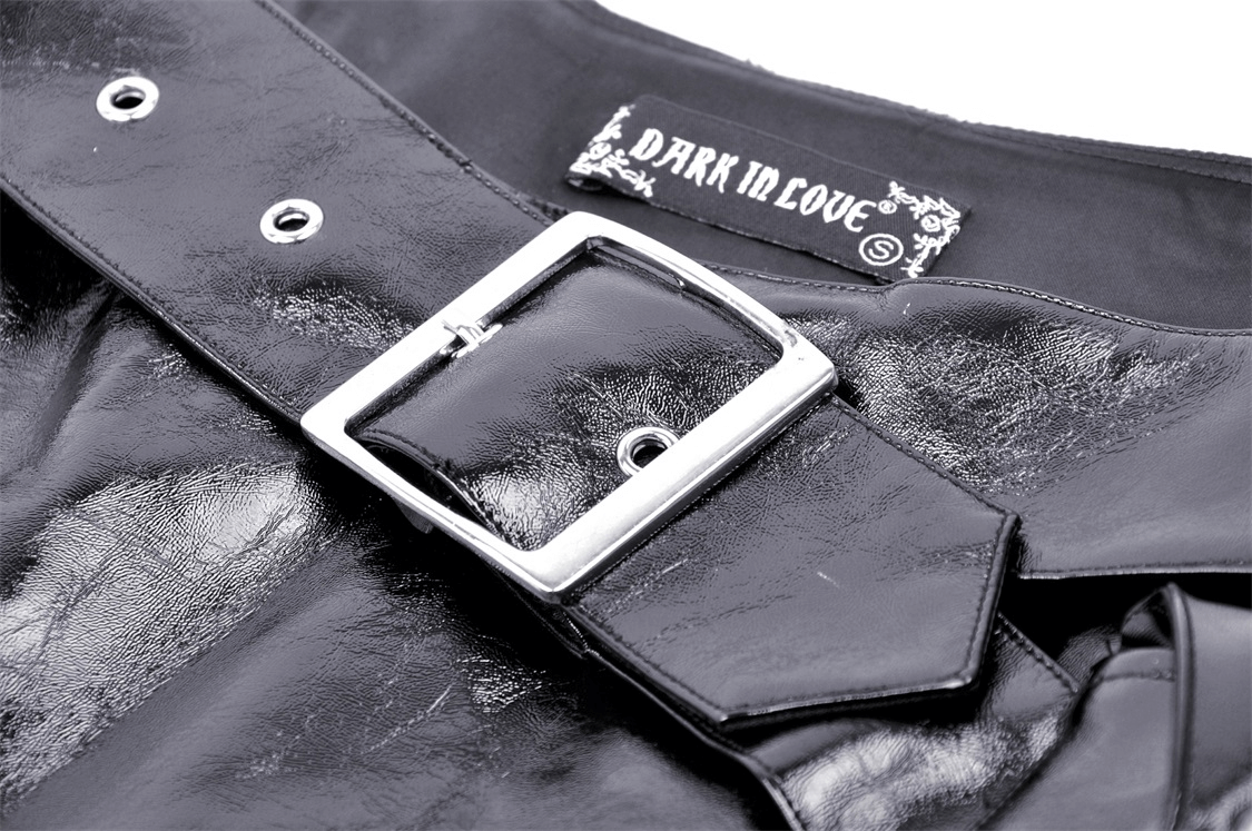 Close-up of a black vegan leather mini skirt with a shiny silver buckle and 'Dark in Love' label, showcasing punk style.