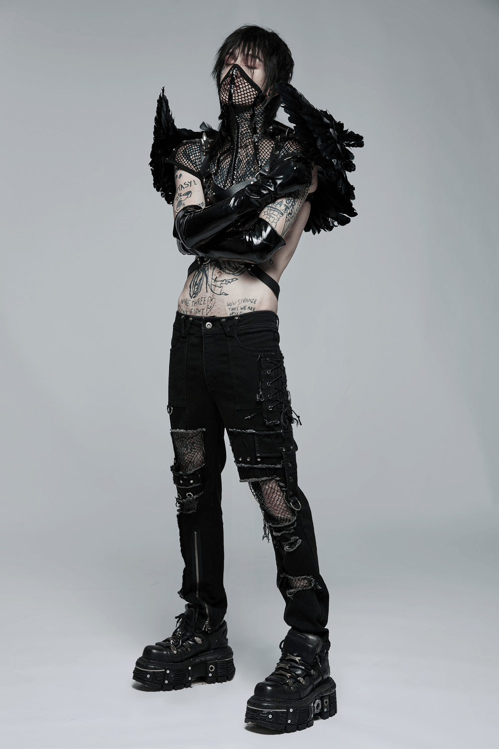 Edgy punk fashion model in black ragged denim trousers, mesh details, and bold metal accents for a rebellious look.