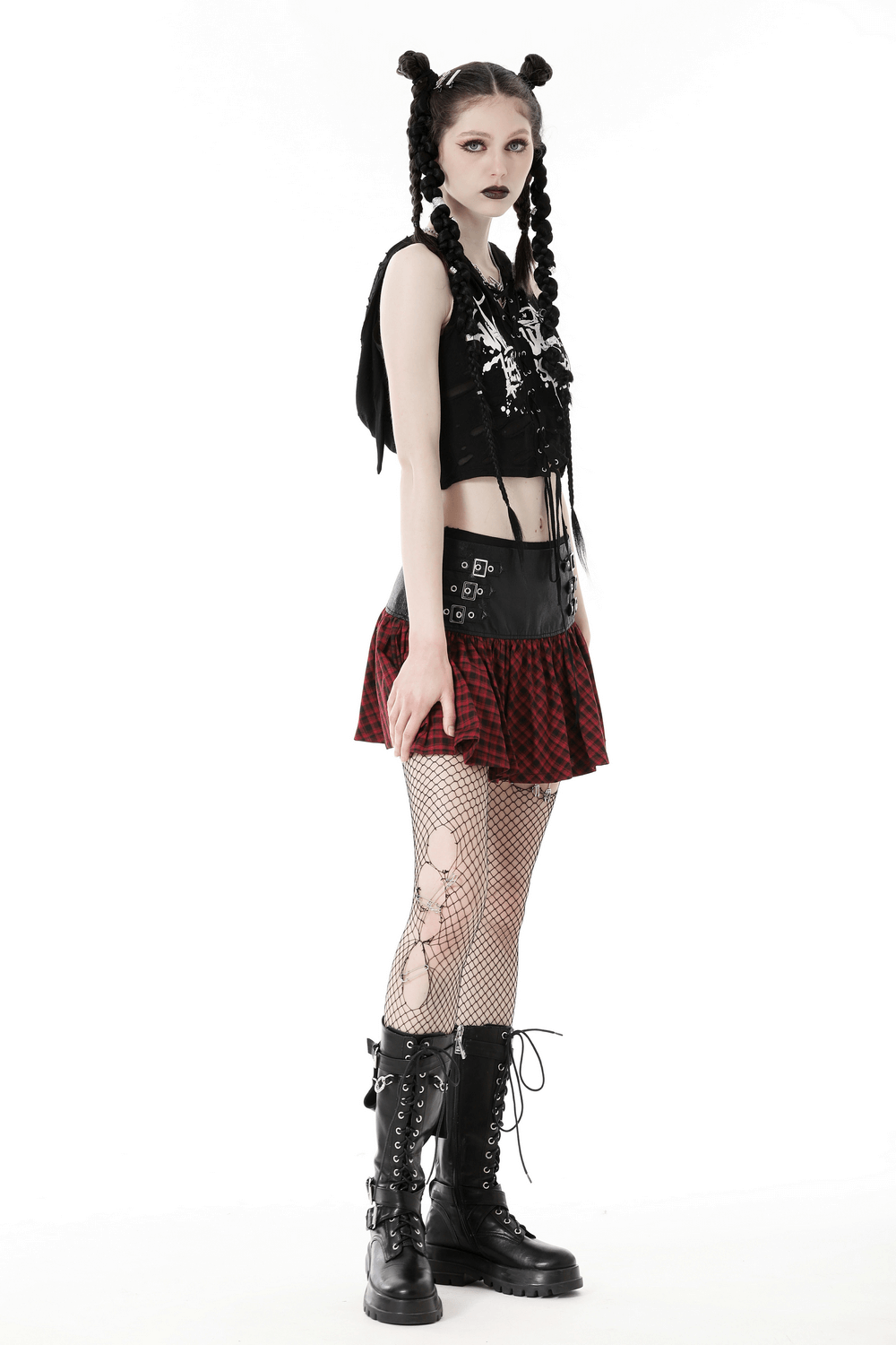 Gothic model in red and black tartan mini skirt, fishnet stockings, and combat boots, showcasing edgy fashion.