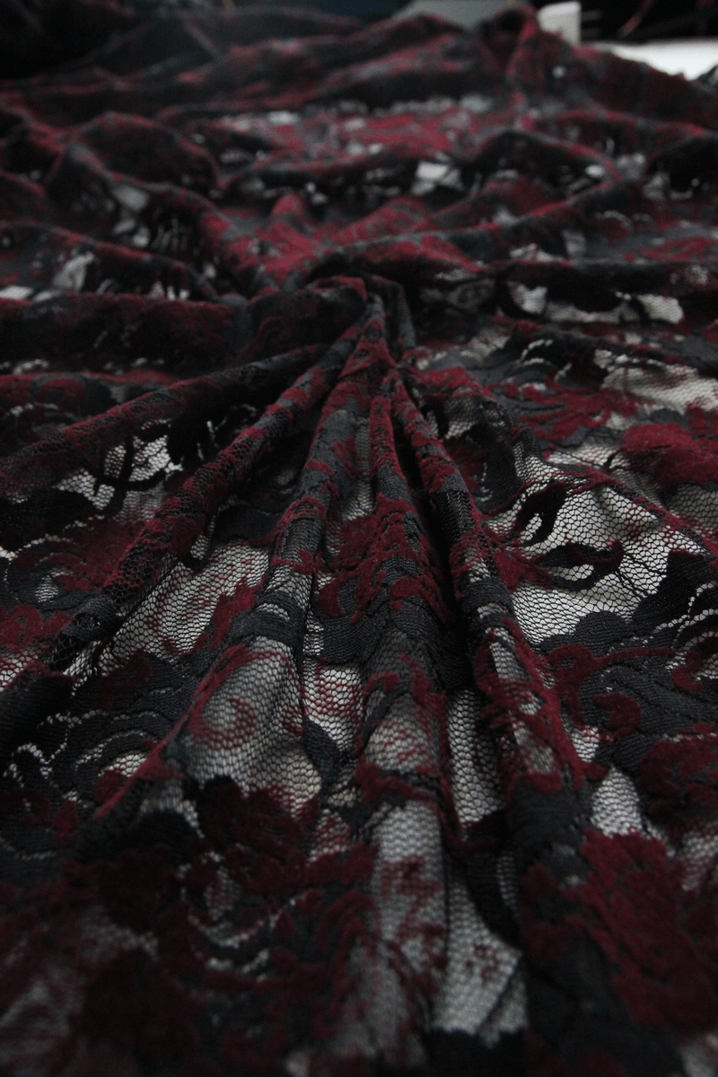 Close-up of exquisite black and red lace fabric showcasing floral patterns for a gothic night dress.