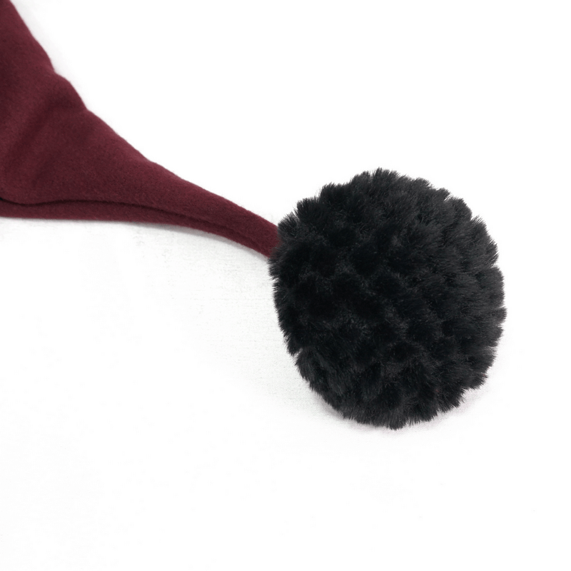 Close-up of a black pompon on the red hood of a gothic short cloak, showcasing vintage style and unique design.