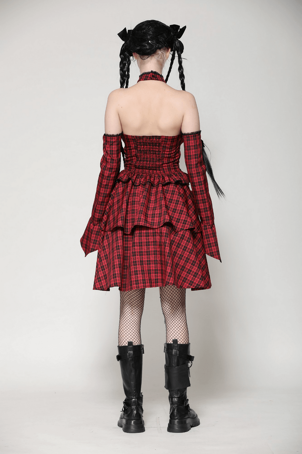 Back view of a red plaid gothic corset dress with ruffles, off-shoulder sleeves, and black knee-high boots.