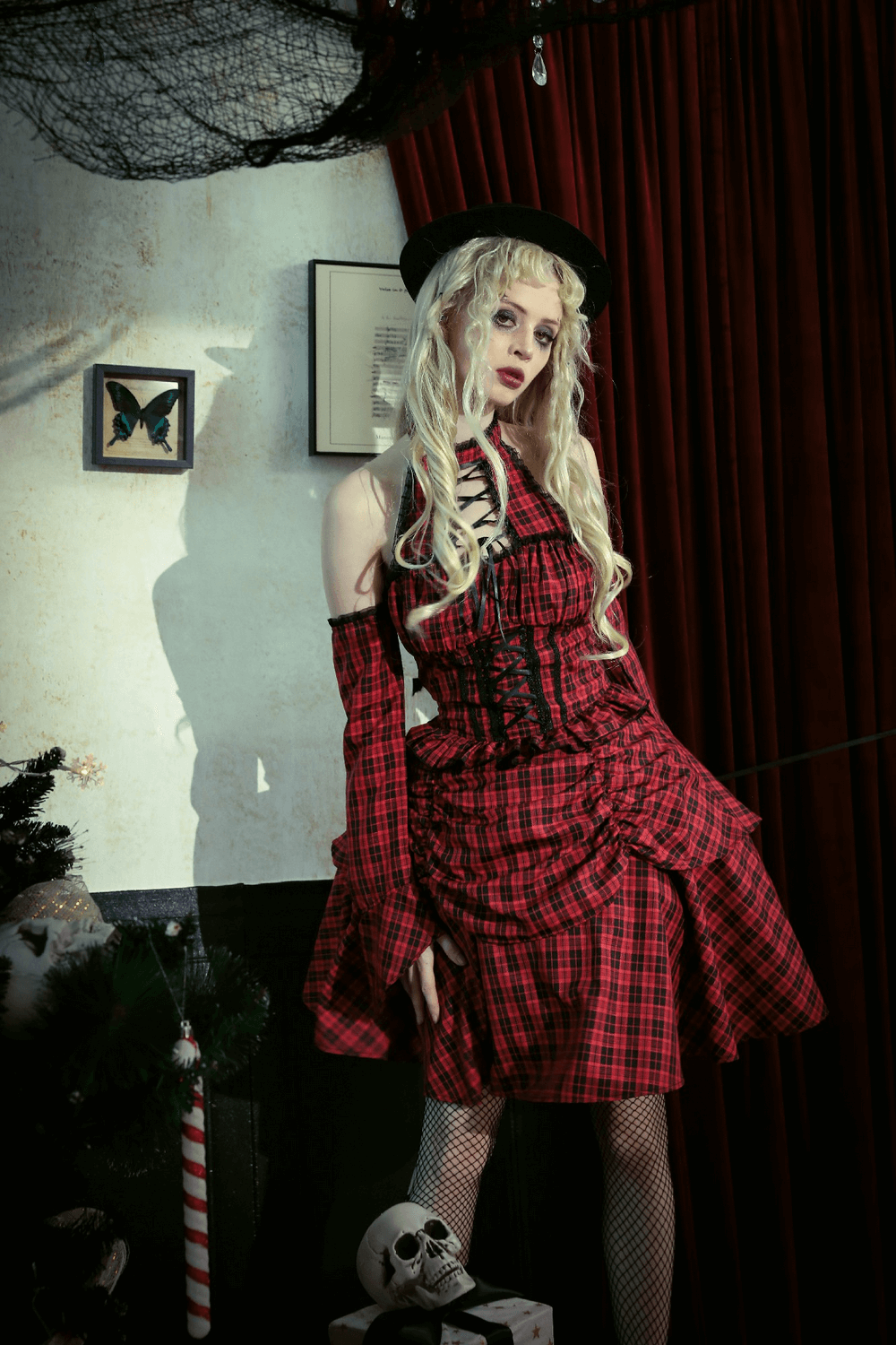 Off-shoulder red plaid gothic corset dress with ruffles, model in a dramatic setting, showcasing Victorian-inspired style.