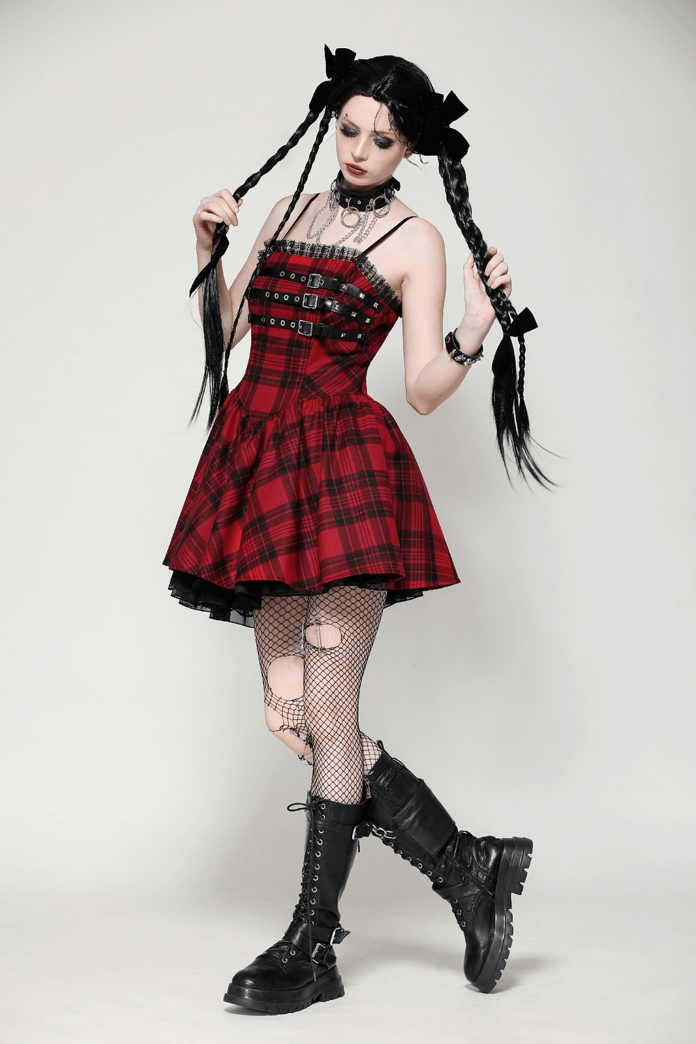 Model in a red plaid Gothic mini dress with buckles, styled with fishnet stockings and combat boots for a punk vibe.