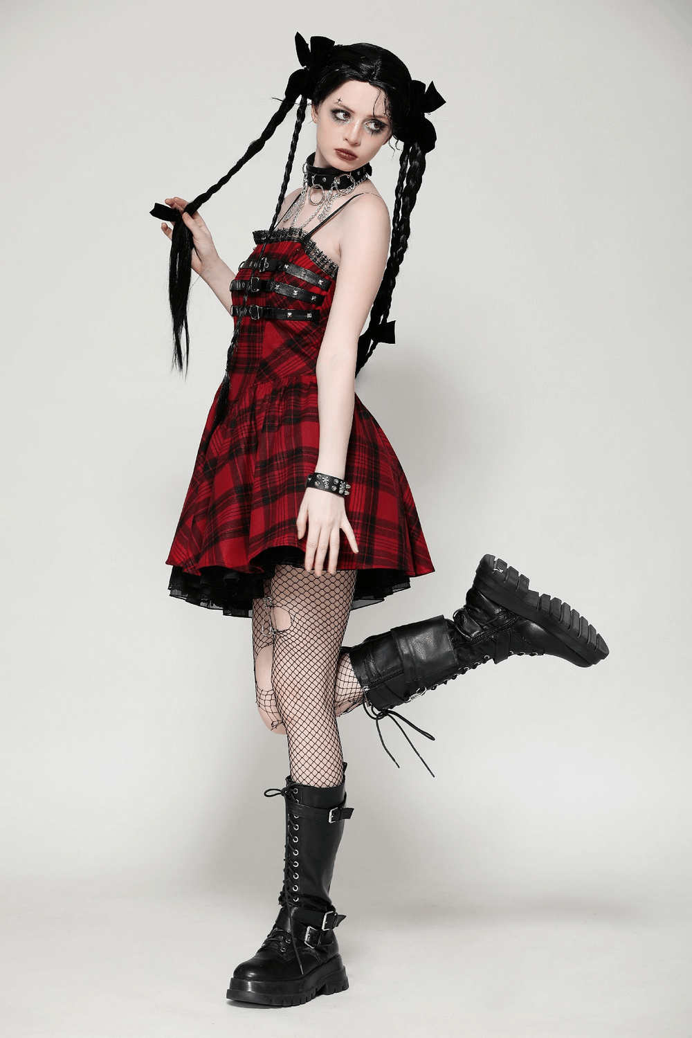 Model wearing a red plaid gothic mini dress with buckle details, showcasing punk-inspired fashion and edgy style.