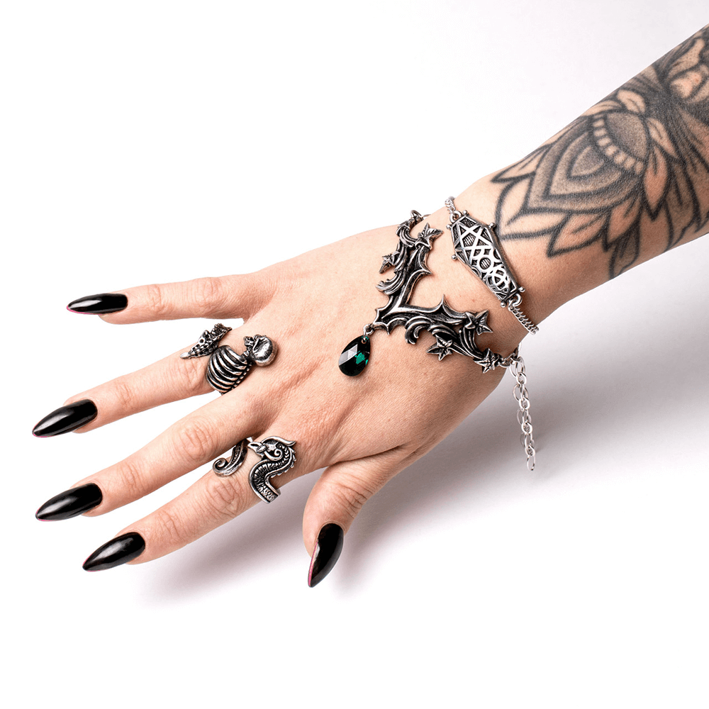 Gothic jewelry displayed on a hand featuring rings, a bracelet, and a stunning skull design in antique silver.