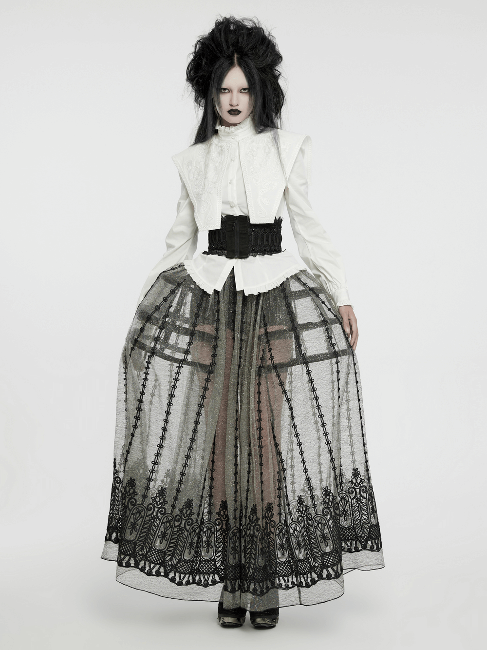Model wearing a retro gothic white ruffled shirt with wide shoulders, paired with a sheer black lace skirt.