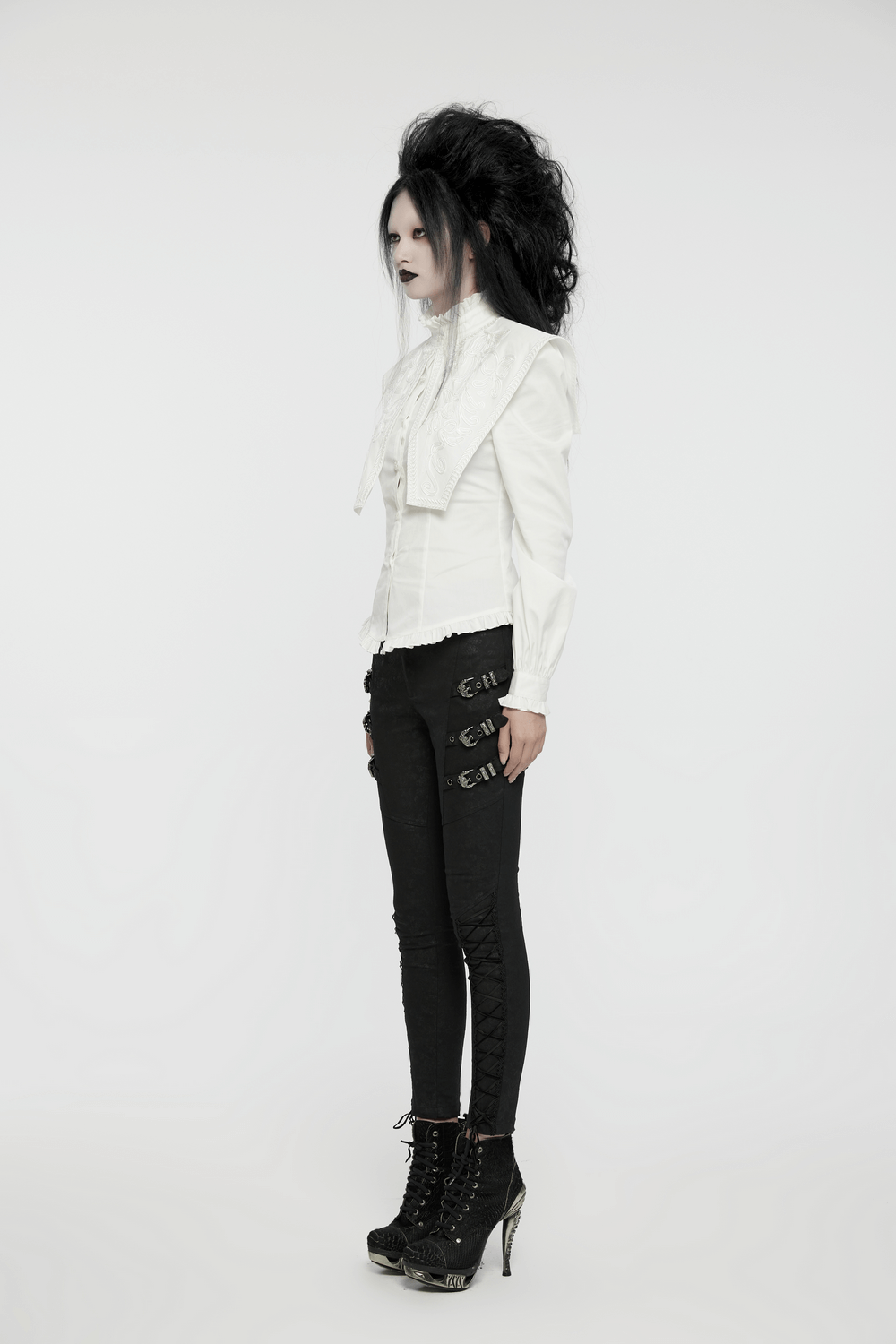 Retro gothic white ruffled shirt with wide shoulders and lace details, styled with edgy black pants and heels.