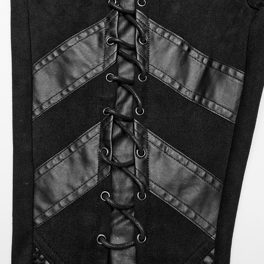 Close-up of black suede flared trousers with eyelet lace-up details and trapezoidal segmentation in gothic style.