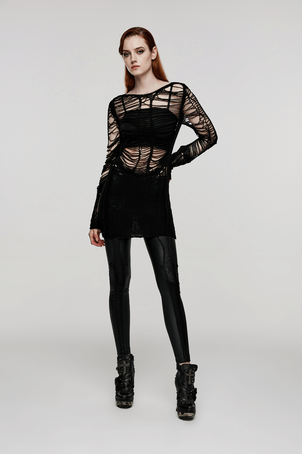 Ripped black gothic punk long sleeve sweater worn by a model, showcasing edgy hollow design and stylish leggings.