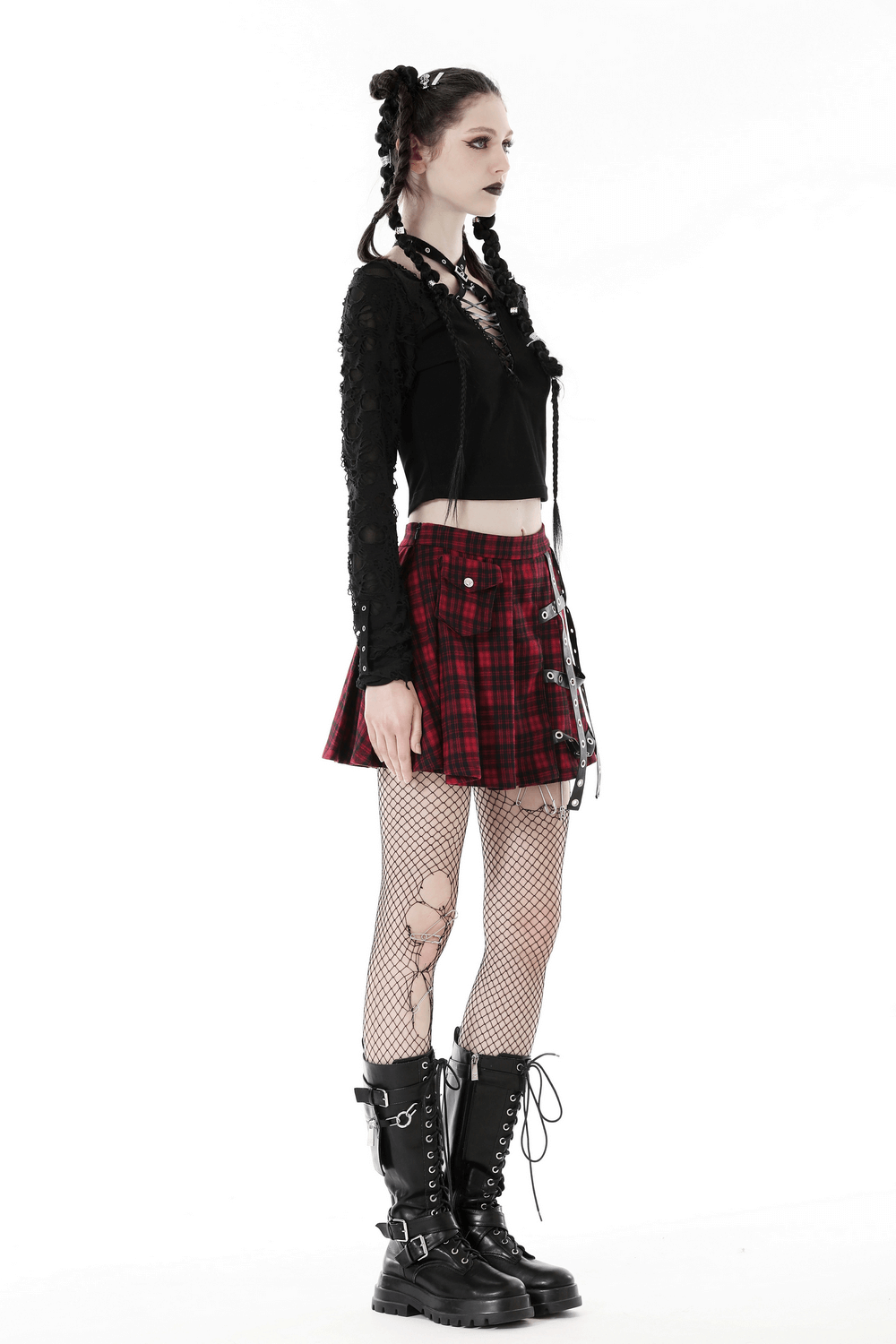 Edgy model wearing ripped long sleeves crop top with lacing, plaid skirt, fishnet tights, and chunky boots for a dark style.