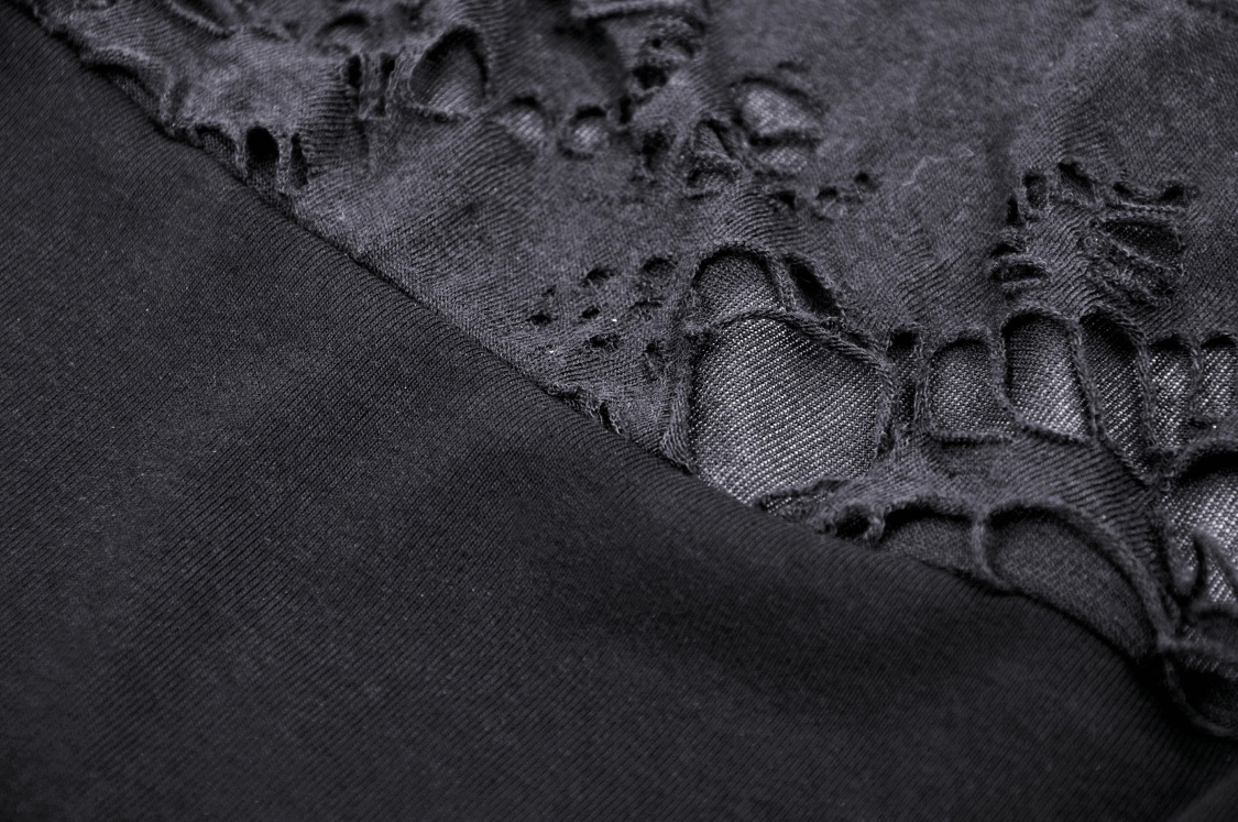 Close-up of ripped black fabric showcasing edgy texture and statement details of a crop top.