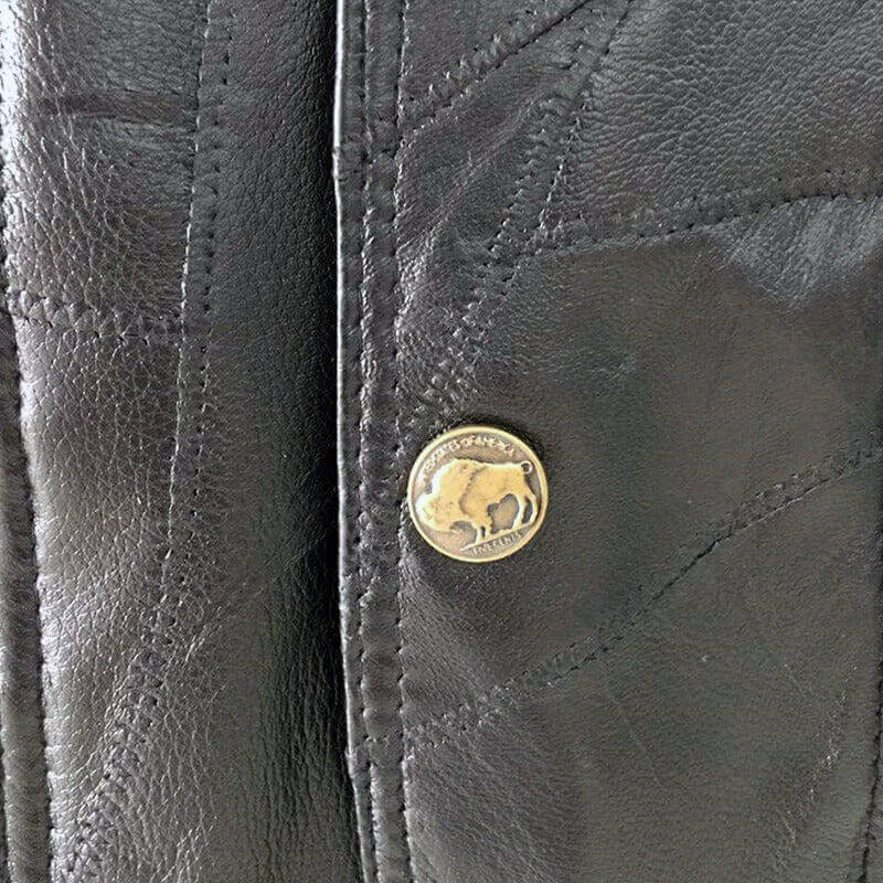 Close-up of a black leather vest showcasing a decorative buffalo button detail for a unique rock style.