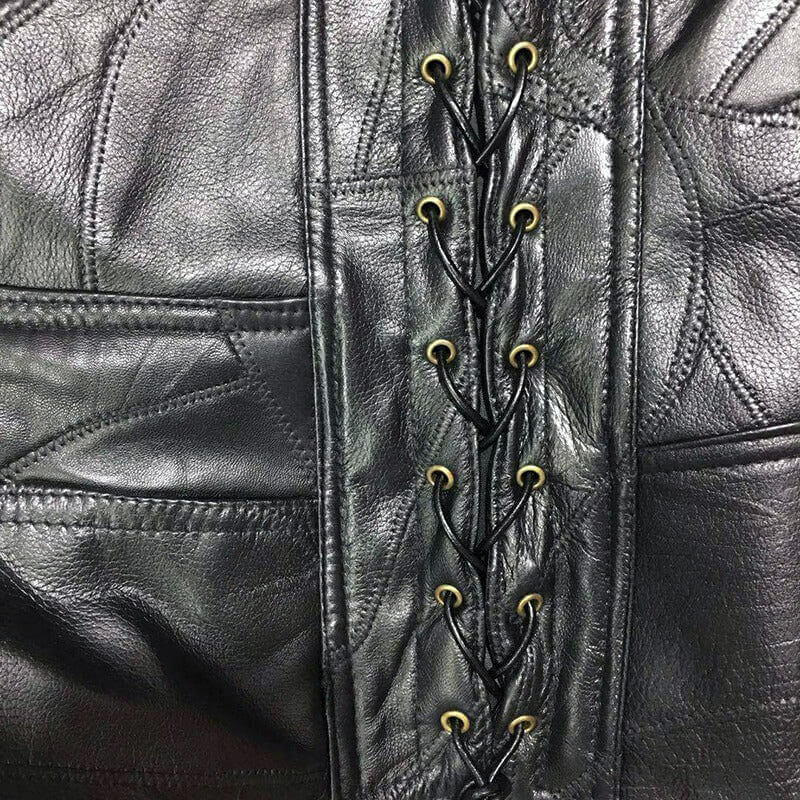 Close-up of black leather vest with decorative lacing and gold eyelets for a punk rock style.