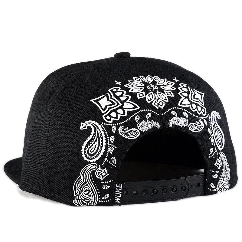 Back view of a black snapback cap with intricate white paisley embroidery, perfect for a rock-style look.