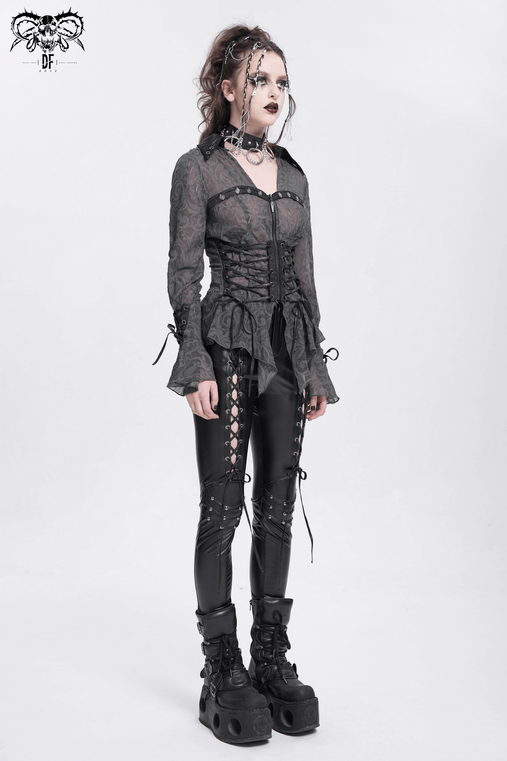 Romantic sheer dark goth blouse with lace-up corset waist, flared sleeves, and pointed hem, styled with edgy black leggings.