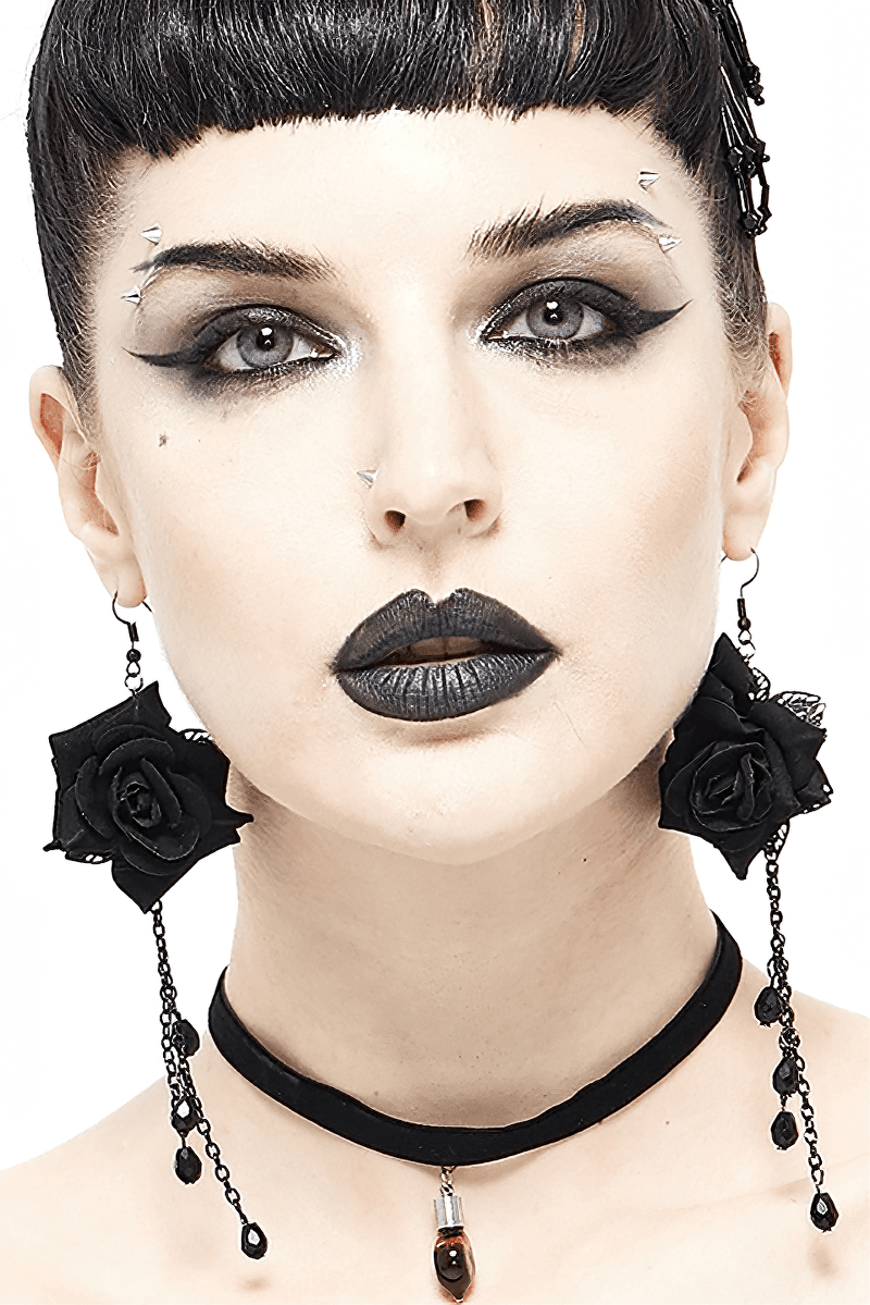 Black rose earrings with chain detail worn by model in gothic style, showcasing alternative fashion jewelry.