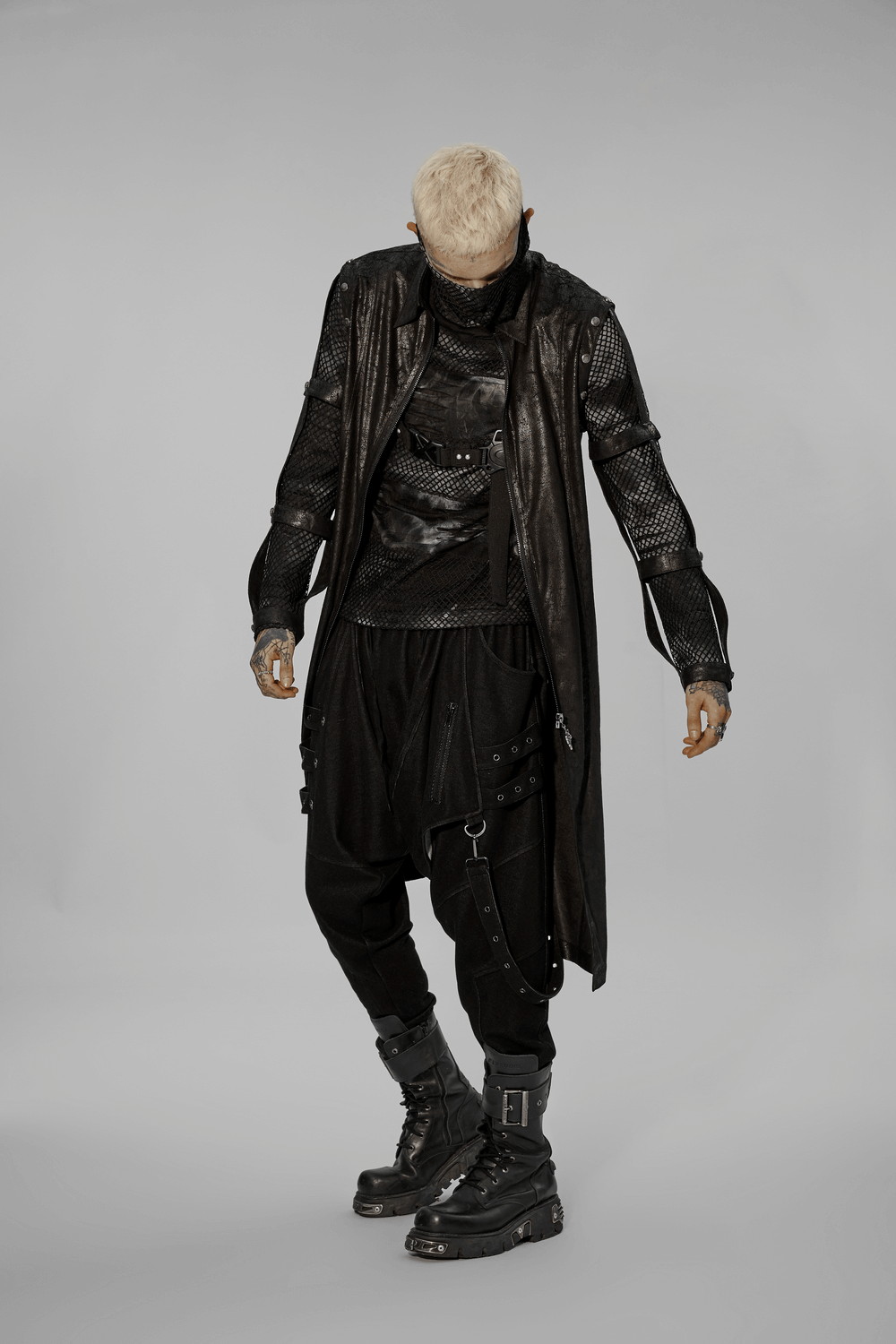 Urban punk fashion model in a long black armored coat with hollow-out details and edgy accessories.