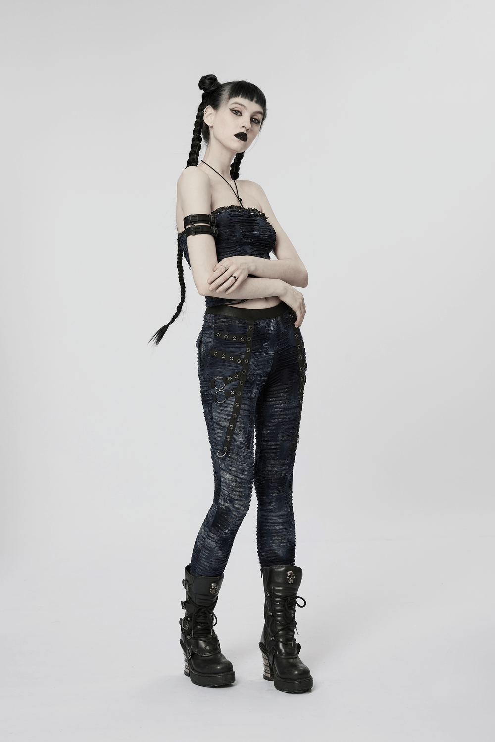 Model showcasing a chic ruched gothic bustier with lace and rivet details, paired with edgy black skinny jeans and combat boots.