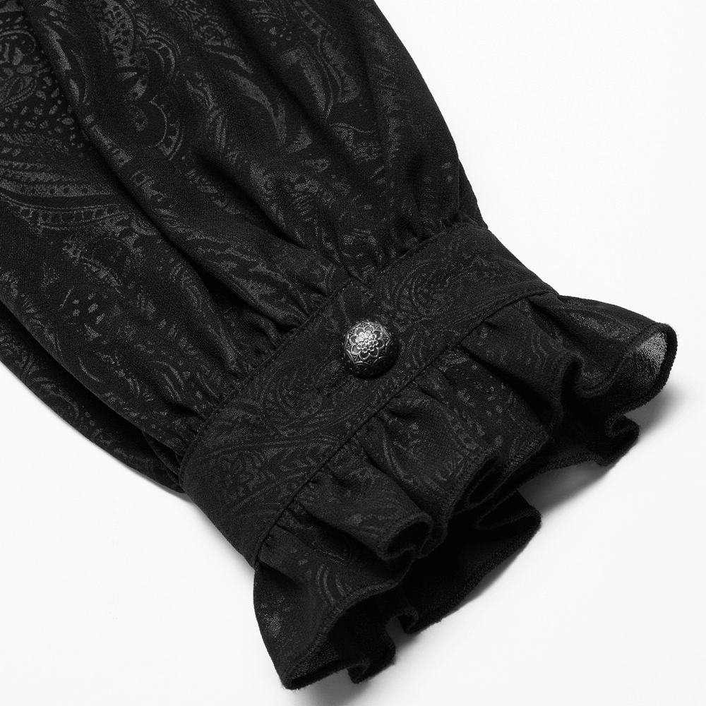 Close-up of a ruffled black Gothic shirt sleeve with elegant button detail and intricate patterned fabric.