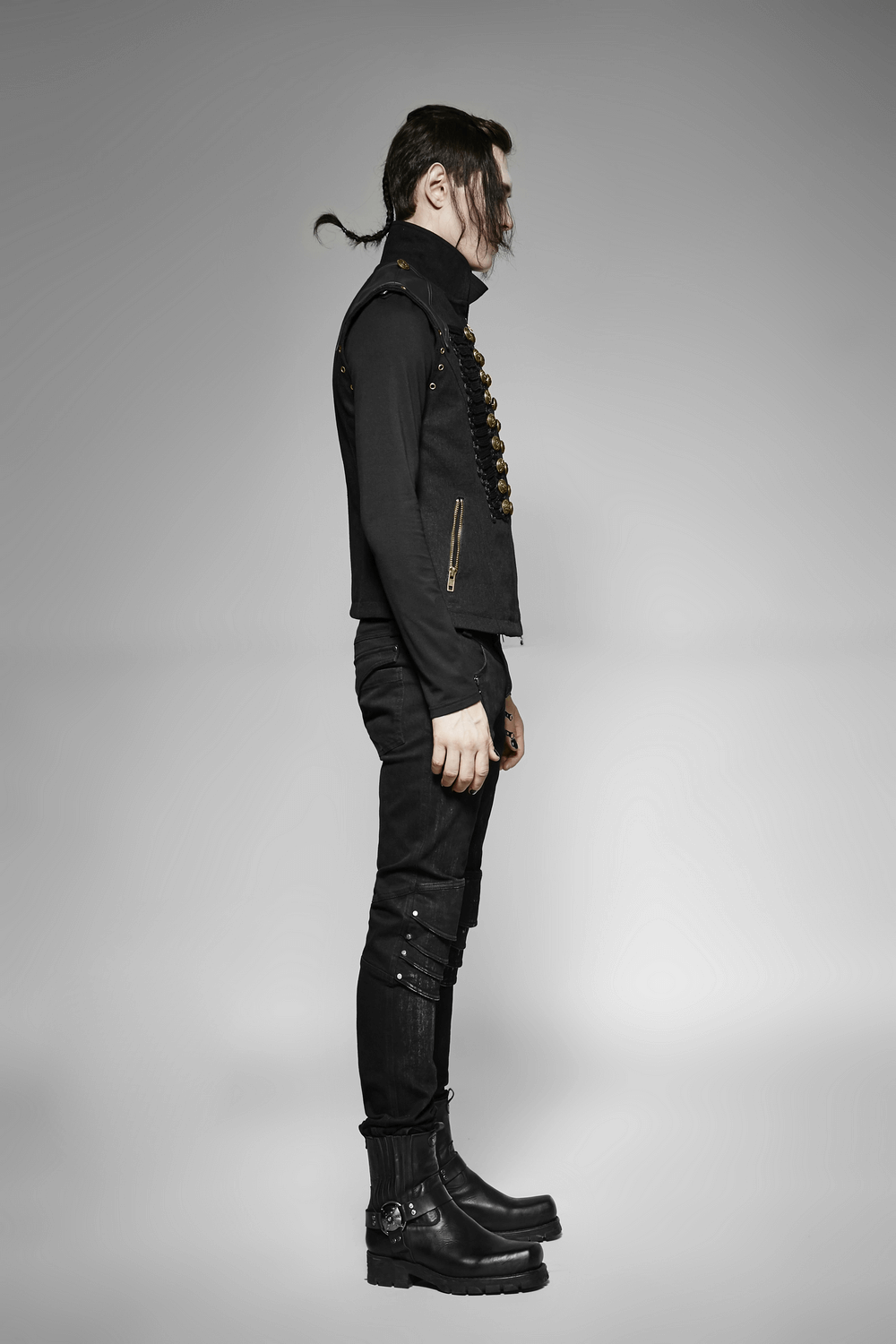 Side view of a stylish male model in a rugged denim military waistcoat with ornate buttons and edgy footwear.