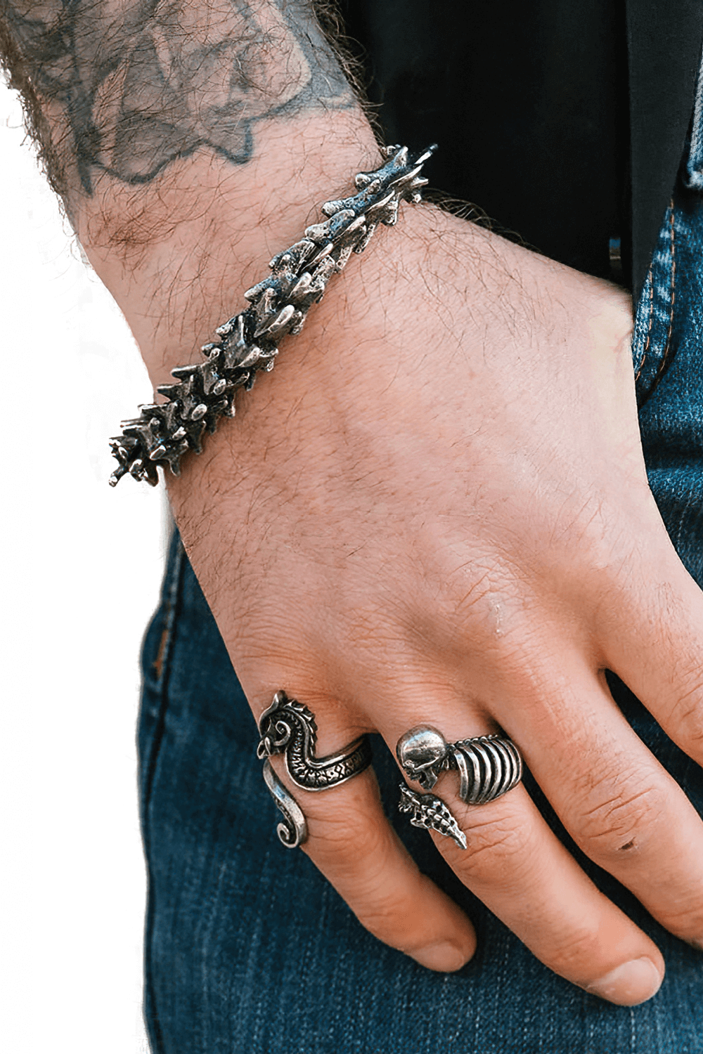 Sculpted pewter vertebrae bracelet worn on a hand with unique rings, showcasing a bold metal aesthetic.