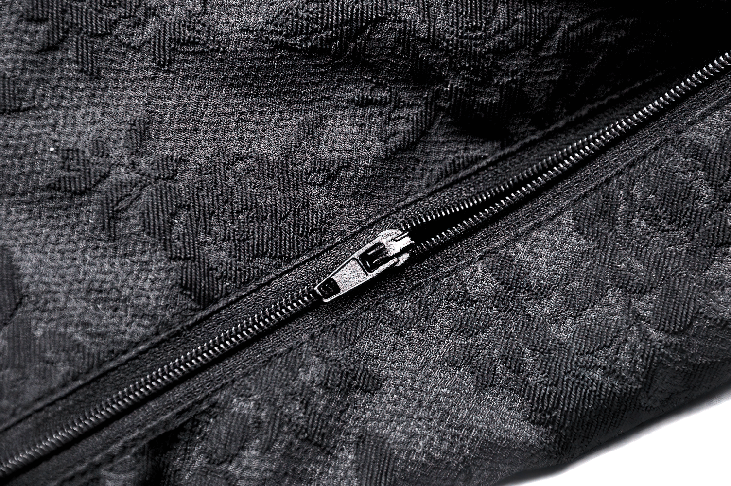 Close-up of a black textured fabric with an elegant zipper detail, showcasing luxury in design and craftsmanship.