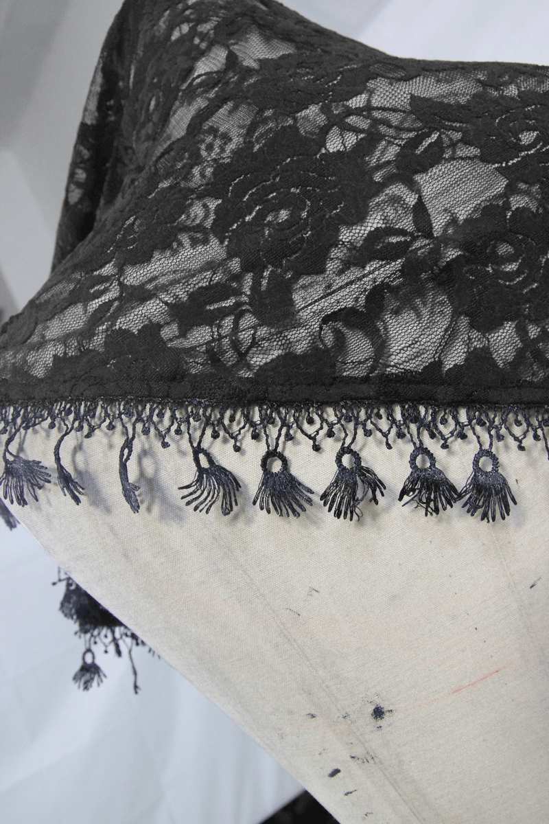 Close-up of elegant black lace fabric with floral patterns and intricate fringed hem, perfect for gothic-inspired fashion.