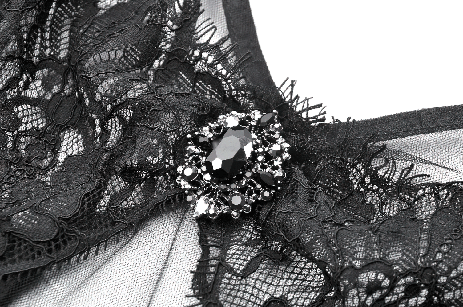 Close-up of intricate black lace detailing and jeweled embellishment on a gothic dress.