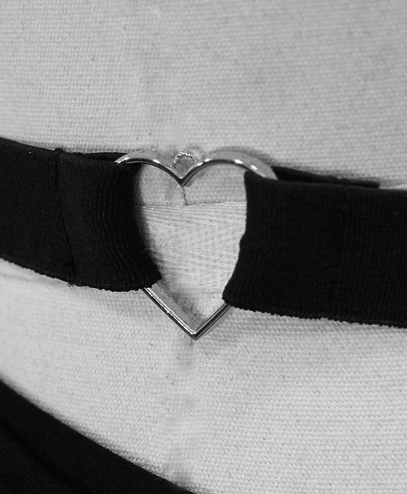 Close-up of a silver metal heart detail on a black strap, showcasing gothic vintage dress elegance.