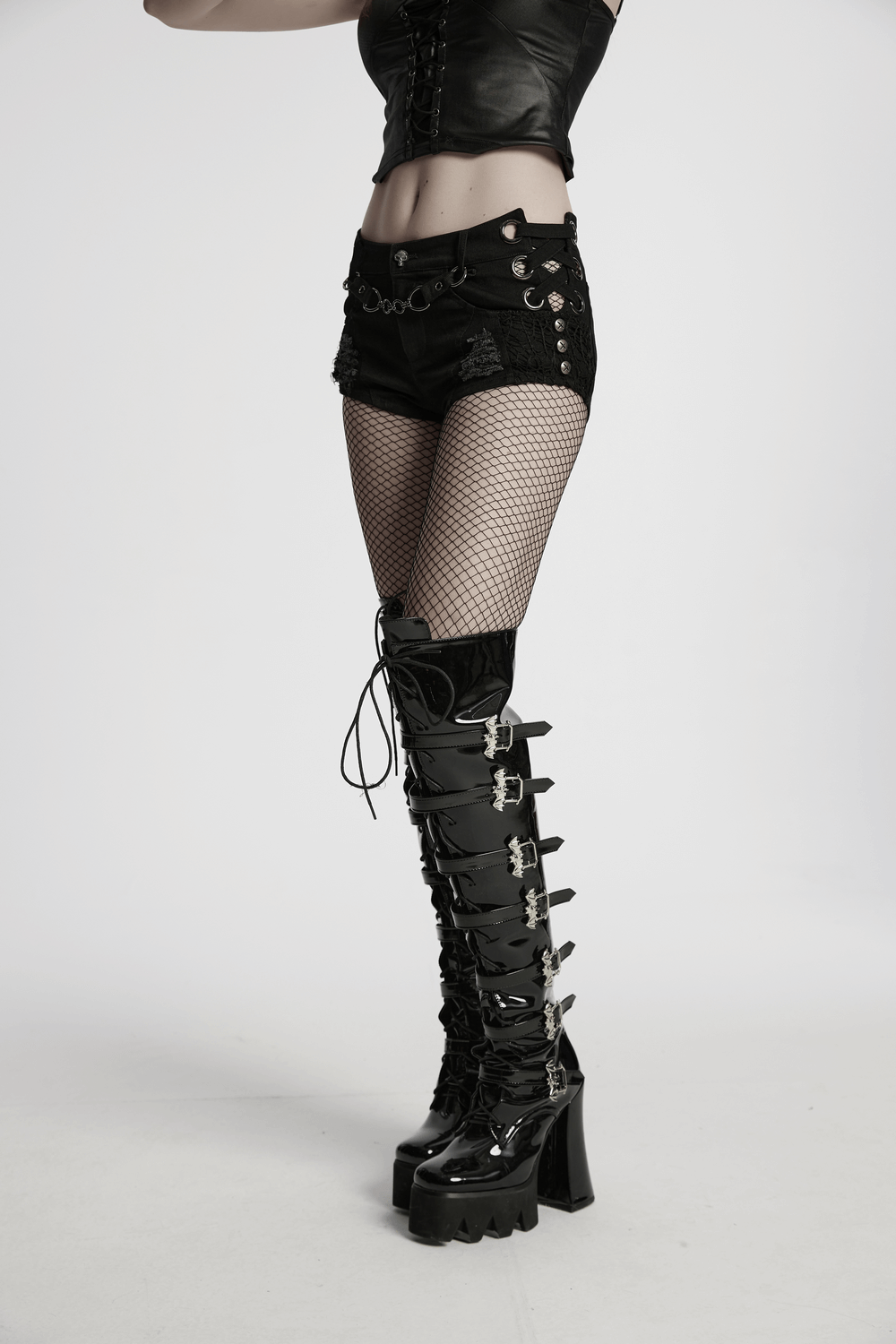 Punk denim shorts with detachable chain, metal eyelets, and fishnet stockings styled with edgy black knee-high boots.