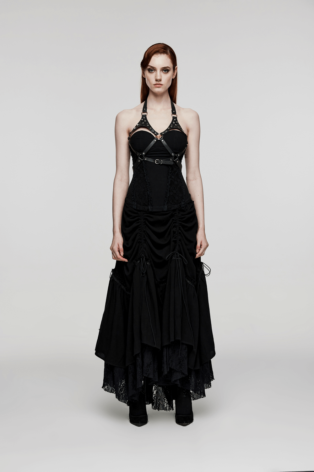 Woman wearing spike-studded faux leather harness with black halter neck design, showcasing a bold punk fashion statement.