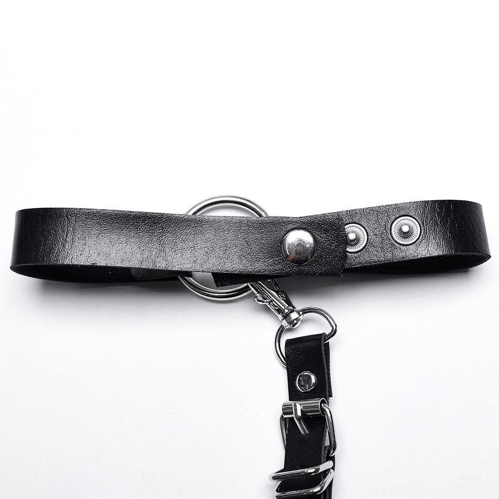 Close-up of a stylish black faux leather harness belt with silver accents and circular ring detail.