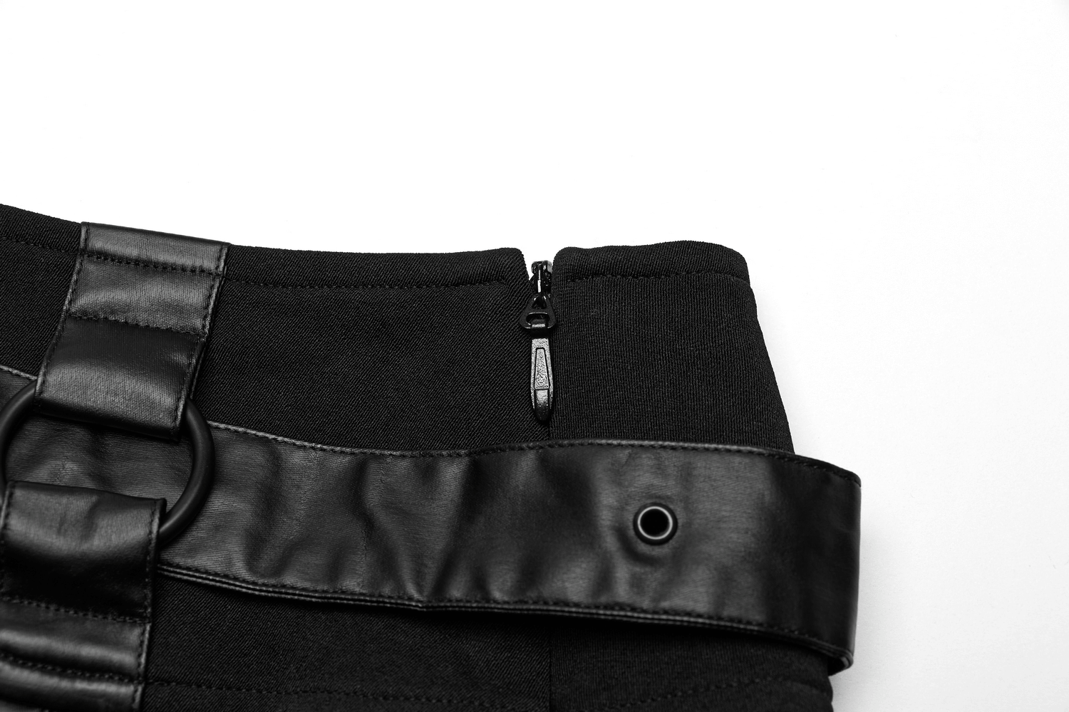 Close-up of a black pleated mini skirt with a faux leather belt and concealed zipper detail.