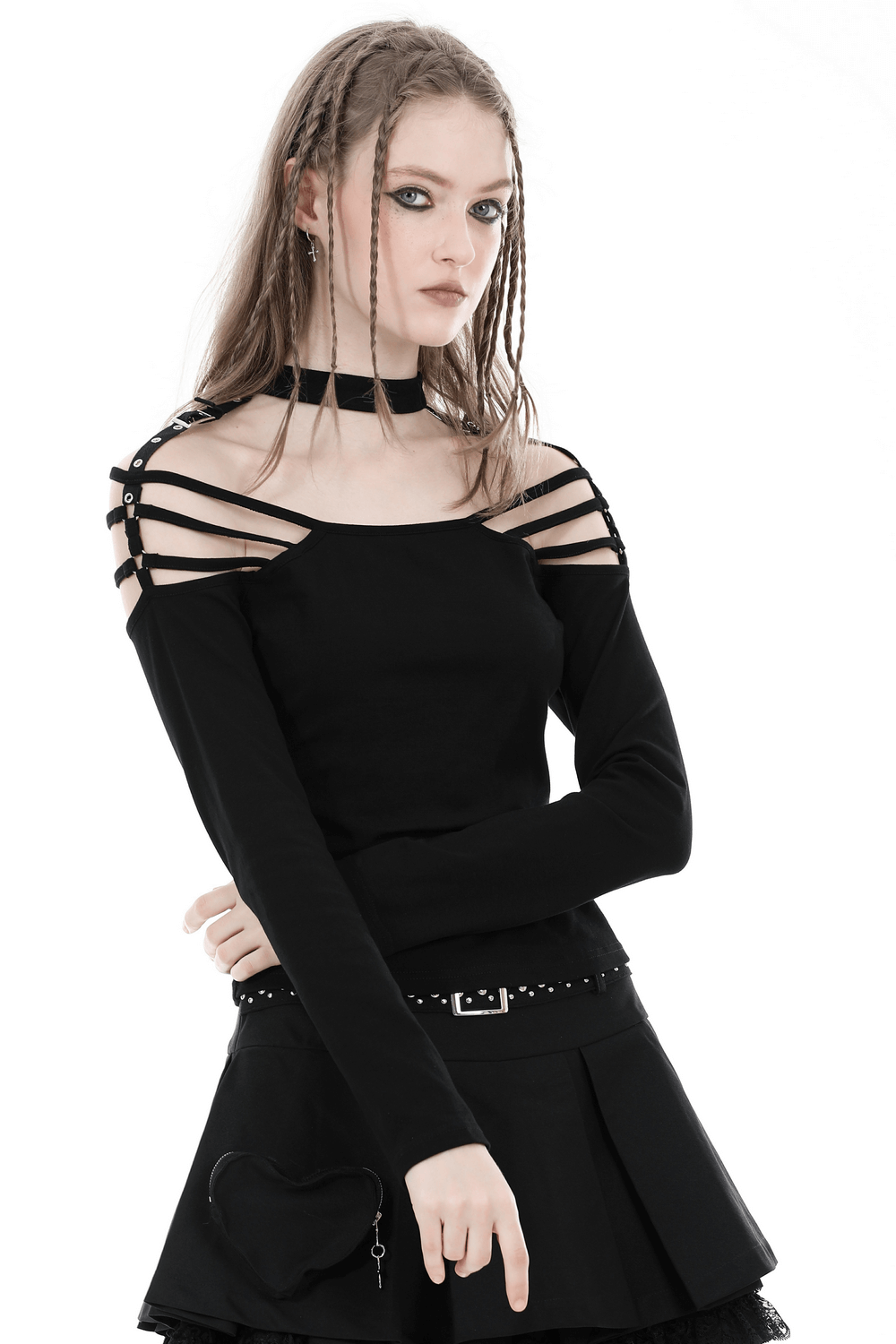 Gothic off-shoulder top with dramatic straps and long sleeves, styled with a skirt for a dark, edgy look.