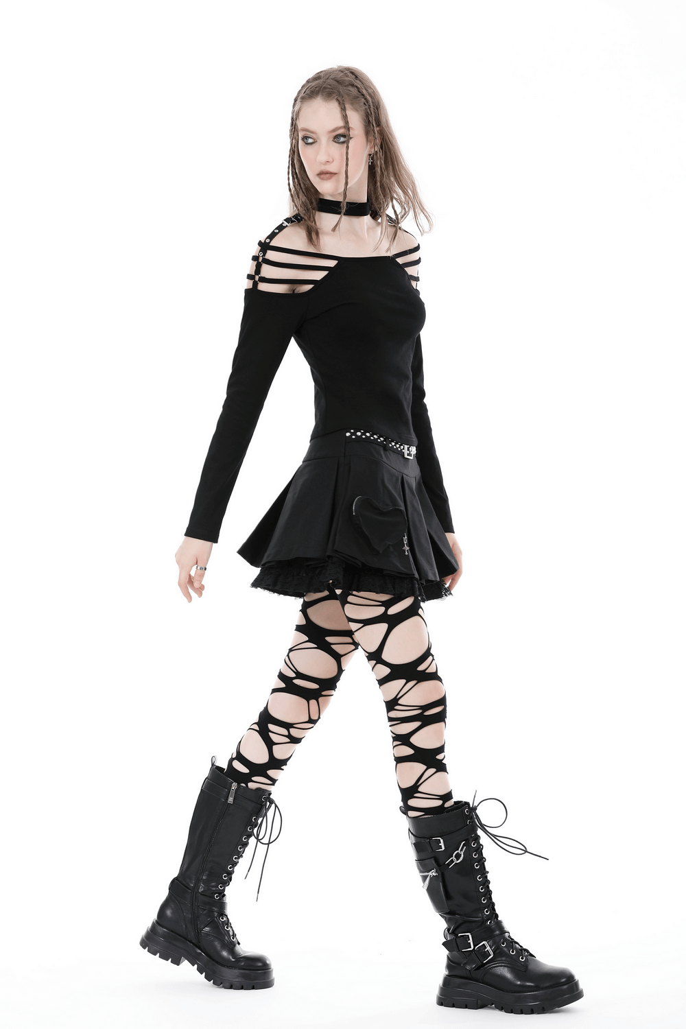 Model in a sexy off-shoulder black top paired with a skirt and lace-up leggings, showcasing gothic fashion.