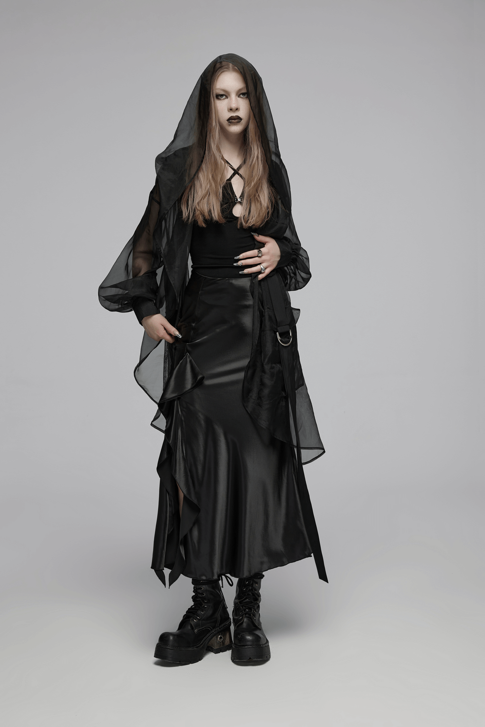 Fashion-forward model in edgy black outfit with hood, showcasing a blend of goth and chic style.