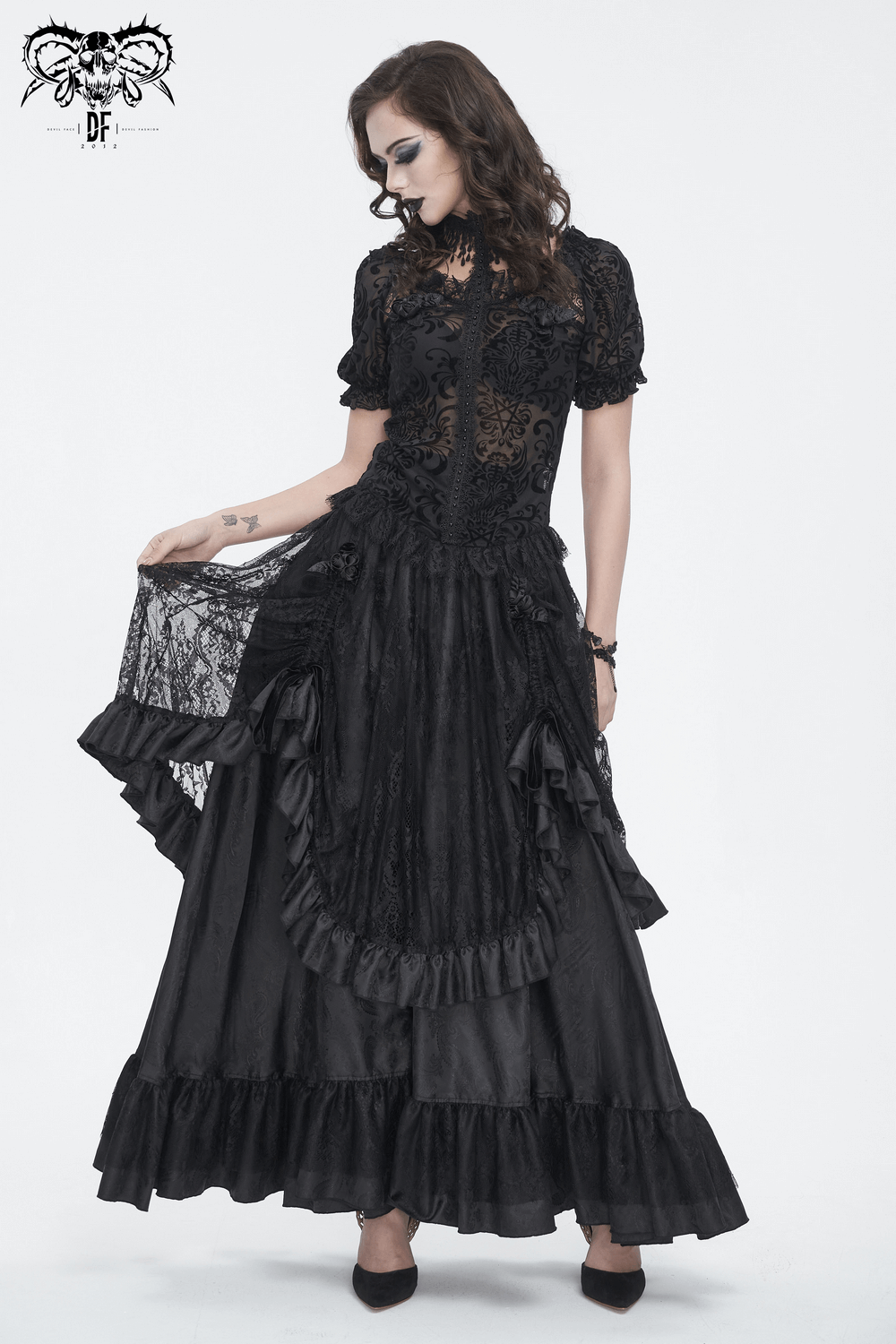 Gothic model wearing a black lace blouse and long ruffled skirt, showcasing elegance and intricate details.