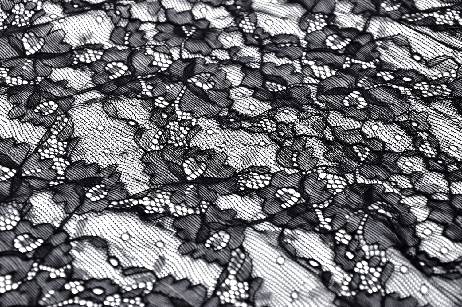 Close-up of luxurious black lace fabric with floral patterns, perfect for gothic fashion and elegant dress designs.