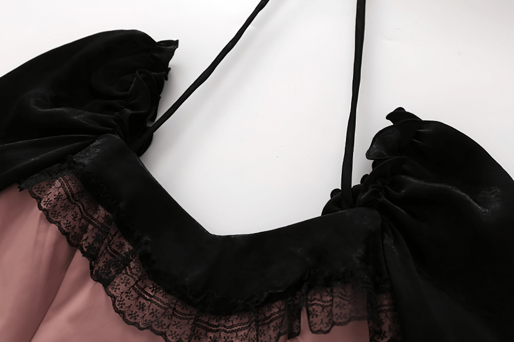 Close-up of the elegant open shoulder design of a pink mesh dress with black lace trim.