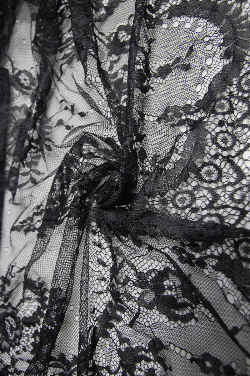 Close-up of intricate transparent black lace fabric, perfect for a gothic romantic dress with delicate details.