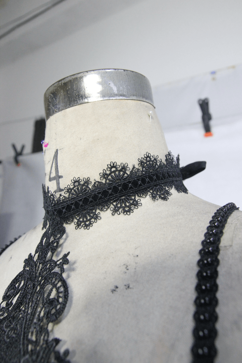 Close-up of a black lace choker on a dress form, showcasing intricate gothic style details and elegant design.