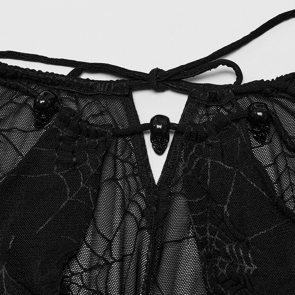 Close-up of gothic dress detail featuring spiderweb mesh and skull embellishments for a dark elegance.
