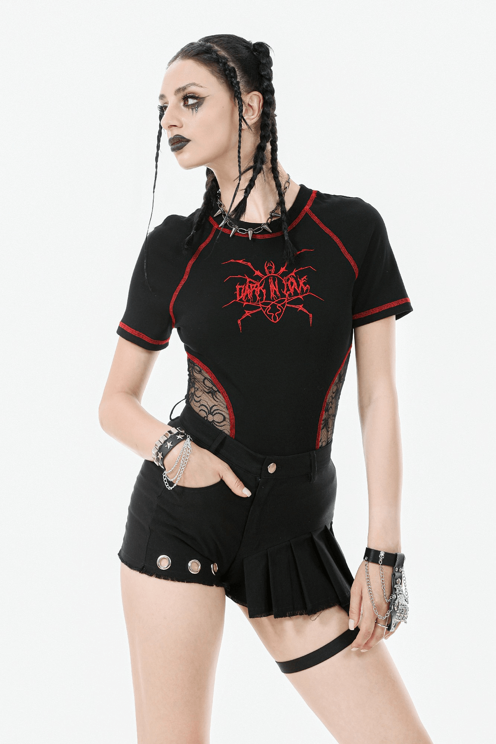Model wearing edgy black pleated shorts with O-ring strap, paired with a graphic top and punk accessories.