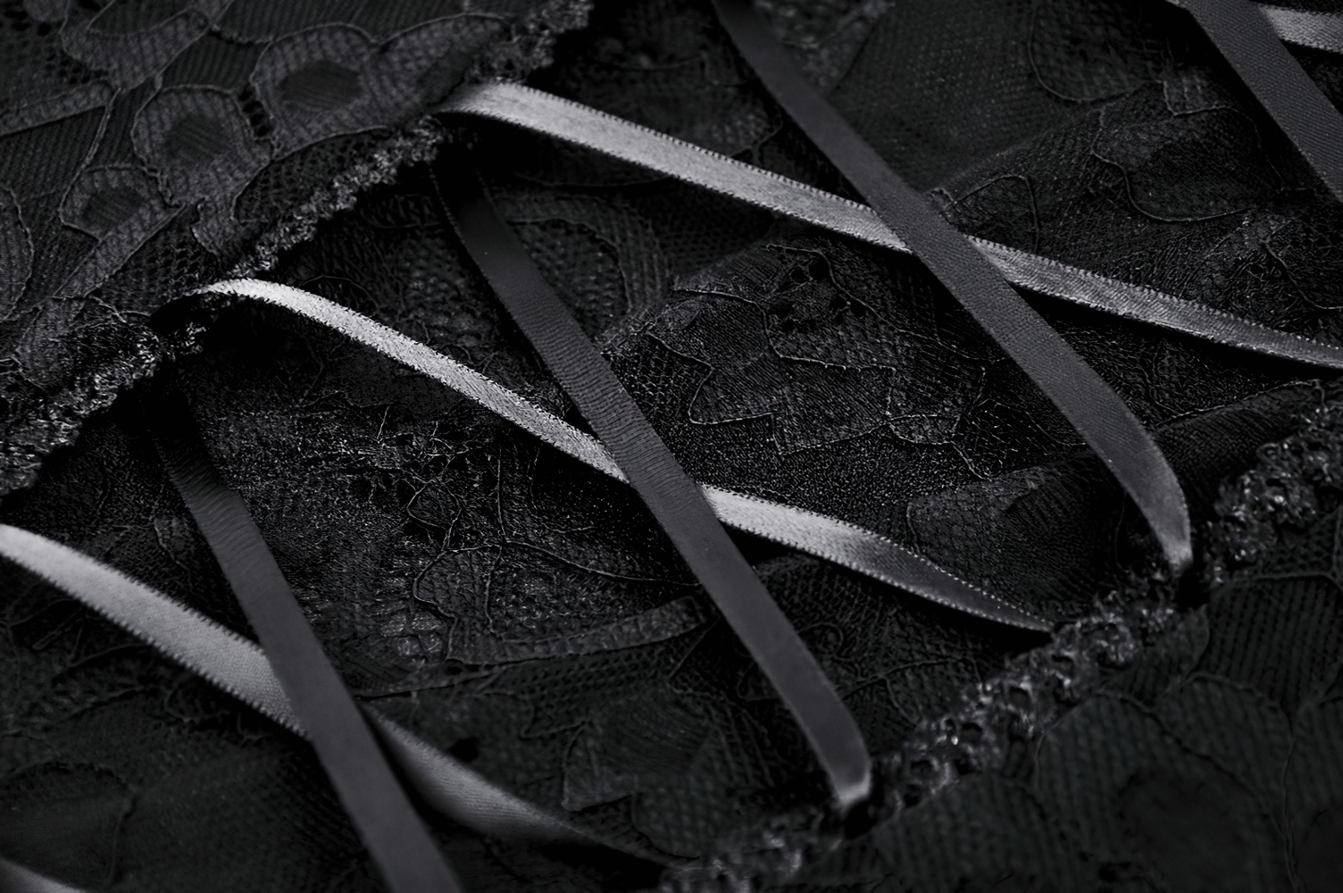 Close-up of black lace fabric with satin ribbons, perfect for a sexy sheer maxi dress design.