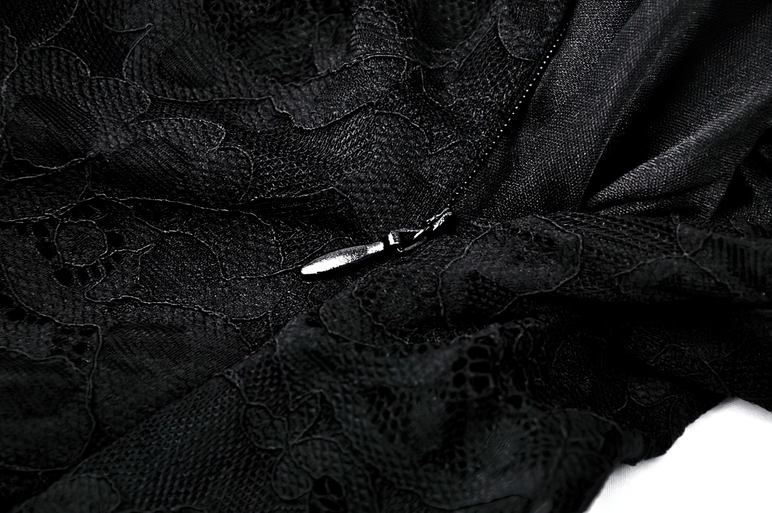 Close-up of black lace fabric showcasing intricate floral patterns and a zipper detail for a sheer black maxi dress.
