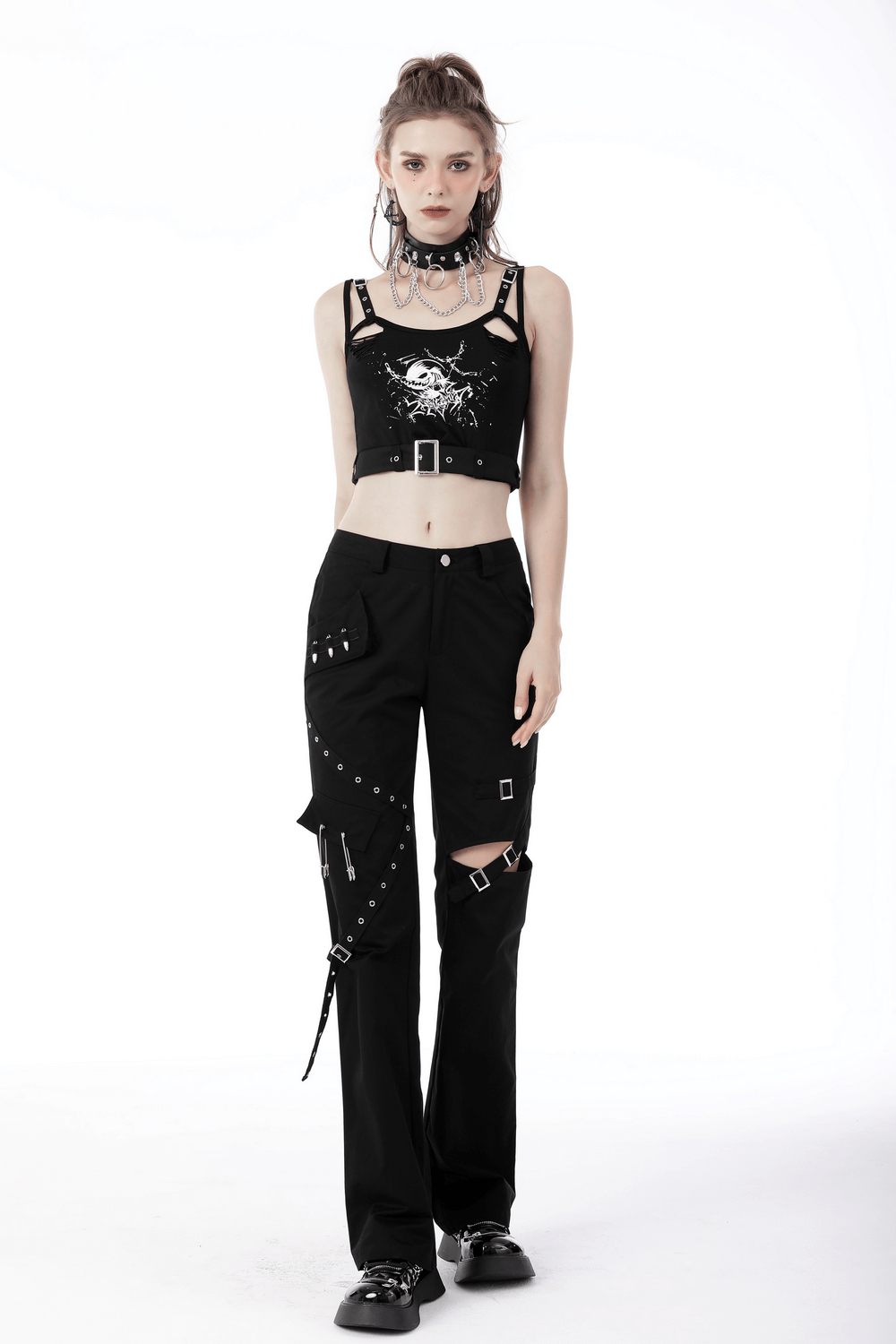 Chic woman in black skull crop top with buckle and edgy black pants showcasing gothic street fashion.
