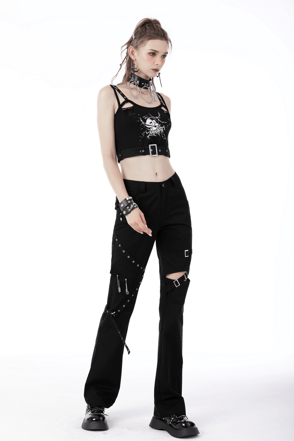 Woman wearing a sexy skull print crop top with buckle and edgy black pants, exuding gothic style.