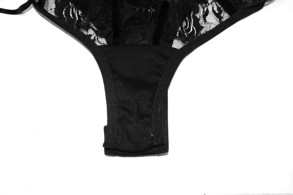 Close-up of a sexy black transparent lace bodysuit with straps, featuring a delicate lace detail.