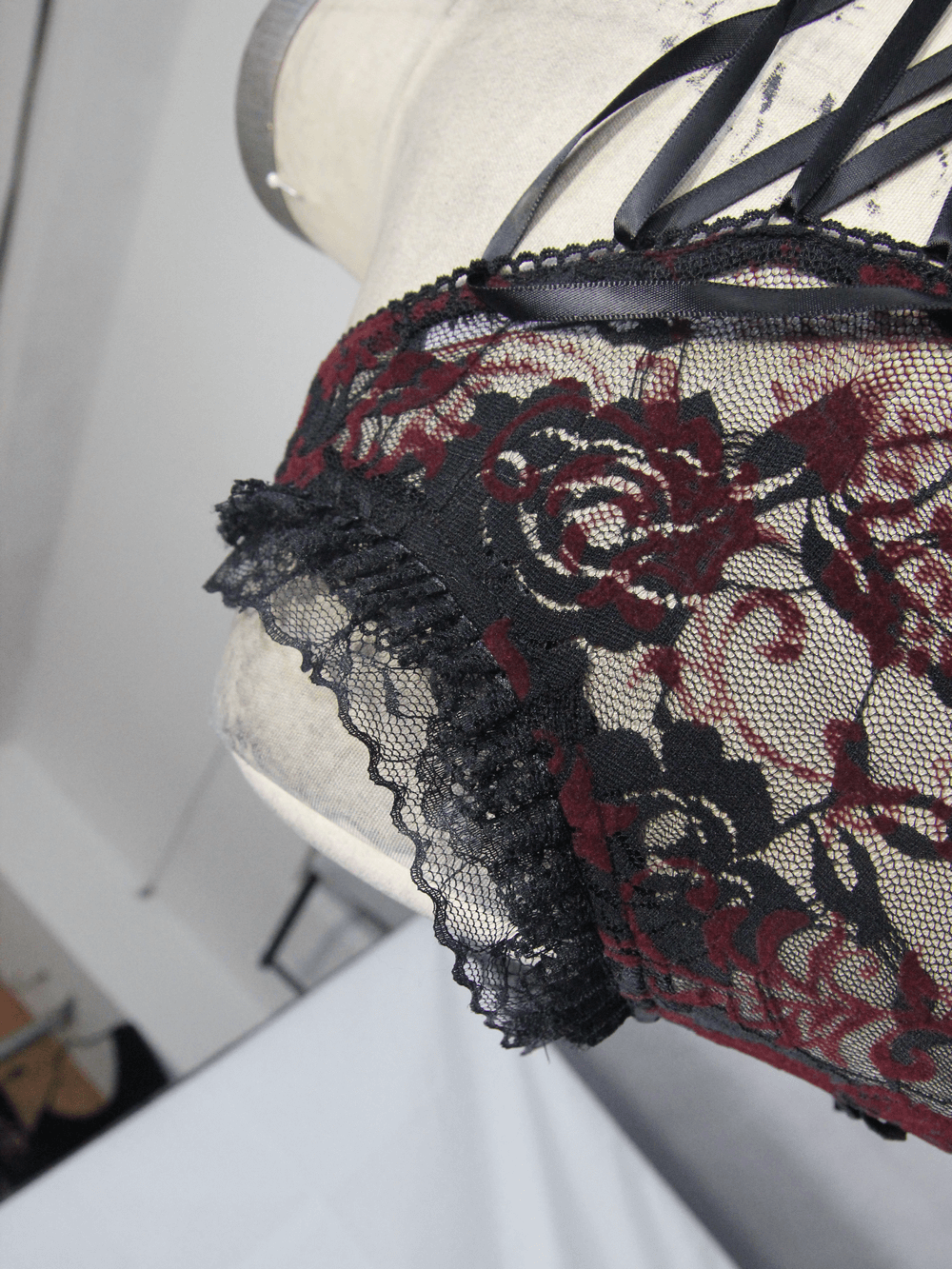 Close-up of black lace with red floral patterns and delicate lace trim, showcasing gothic style details.